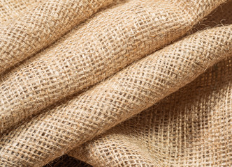 Crumpled burlap textile, close up view. Texture of brown sackcloth. Brown baline, abstract background. Selective soft focus. Blurred background