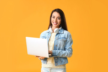 Beautiful young woman with laptop on color background