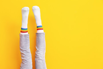 Legs of young woman in socks and jeans on color background