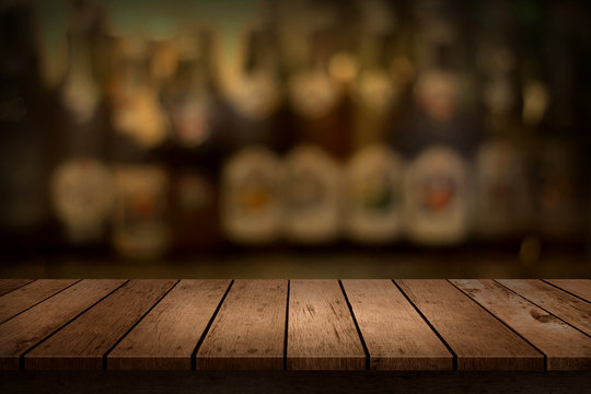 Wooden table with a view of blurred beverages bar bottle background. For create montage product display.