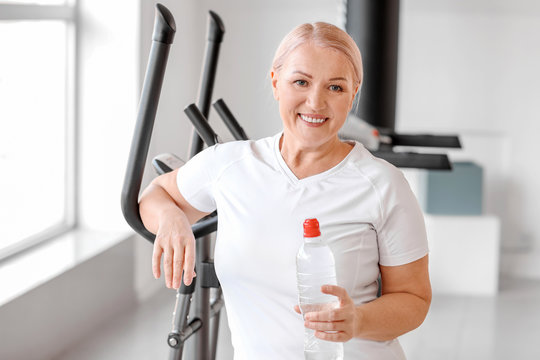 Sporty mature woman with bottle of water in gym