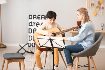 Private music teacher giving guitar lessons to little boy at home