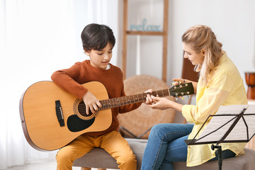 Private music teacher giving guitar lessons to little boy at home