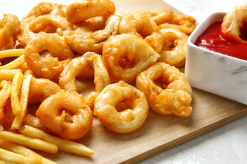 Crispy onion rings, french fries and sauce on table