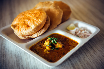 Puri bhaji, close up. Poori masala, fried indian bread. South Indian breakfast Puri with gravy and chutney on wooden table.
