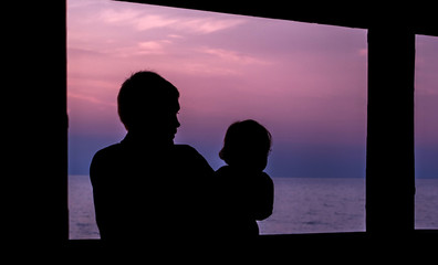 A father shares a beautiful colorful sunset over the lake with his infant daughter 