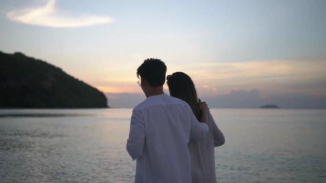 Young people taking evening walk by the sea, young man holding wine glass in one hand and hugging his girlfriend with another slow motion