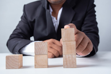 Businessman Wooden cubes on a desk in the office, Concept: Business to succeed that challenges teamwork,  design development strategy investment, symbol Financial advisor shows  to asset growth