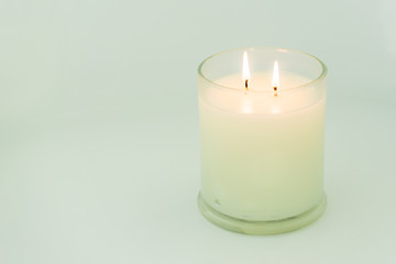 Burning white candle, with two wicks, viewed from the side on a plain background, landscape orientation