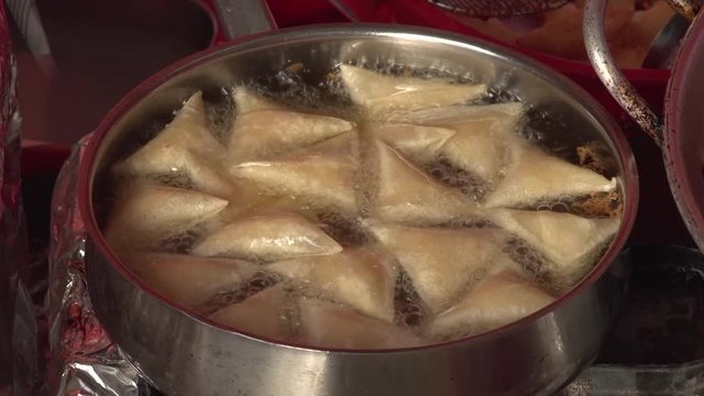Samboosa being deep fried in hot oil in a pan during Bahrain's food festival. Samboosa is a traditional dish with many varieties all over the east from India to Baghdad and the Arabian Gulf.