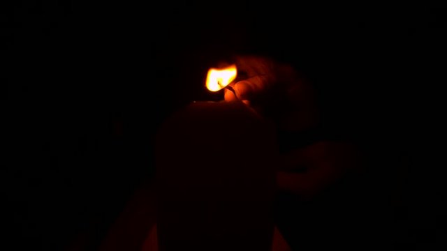 Lighting a candle with a match in the dark.