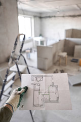 The construction worker hold in hands Architectural blueprints. Repair or construction of a new...