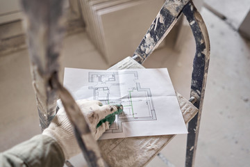 The construction worker hold in hands Architectural blueprints. Repair or construction of a new apartment. Concept for new house design or home improvement. Development of the apartment project.