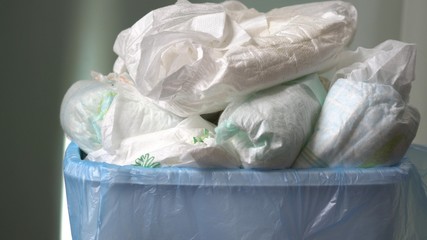 Bathroom garbage (grey) cart for diapers. Mother throws dirty diapers into the trash. Disposing of...