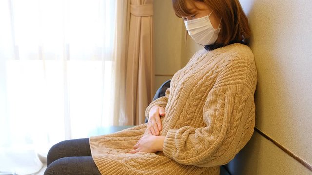 病院の待合室でお腹をさする女性　妊婦　妊娠　ママ　産婦人科　出産