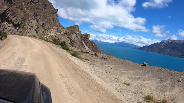 Car moves on the narrow curved road near the lake of General Carrera in Chilean Patagonia