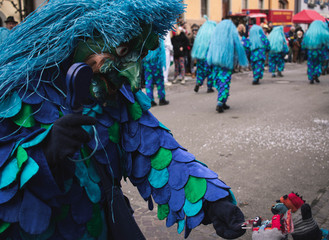 Blauer Narre mit Fisch Maske überreicht Süssigkeiten an Kind bei Karnevalsumzug in Meersburg