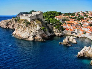 old fortress on a rock and part of the city of Dubrovnik on a sunny clear day, blue sea washes the coast, Montenegro