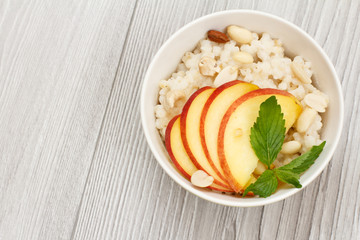 Sorghum salad with nuts and fresh peach on wooden background.