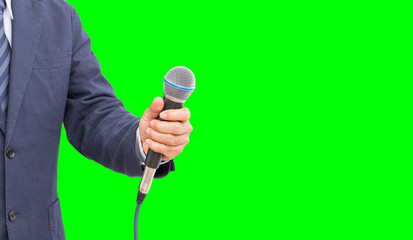 Unknow reporter hand holding microphone on green background with copy space