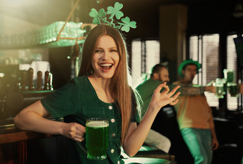 Young woman with glass of green beer in pub. St. Patrick's Day celebration