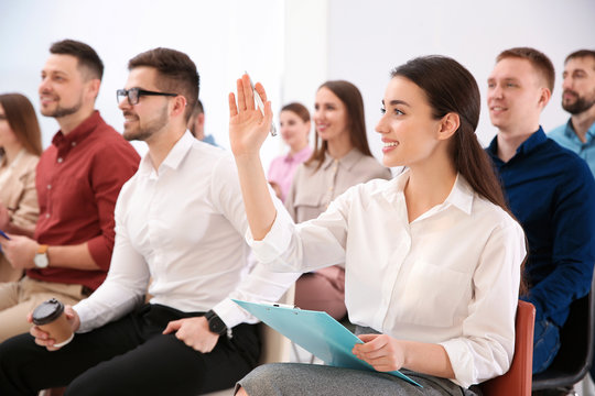 Young Woman Raising Hand To Ask Question At Business Training Indoors