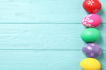 Colorful Easter eggs on light blue wooden background, flat lay. Space for text