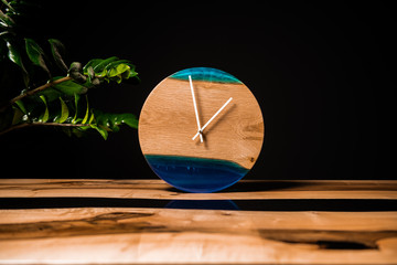 Round eco clock made of wood and epoxy. The subject of interior in your home. Natural handmade tree. Clock on the background.