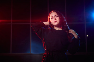 Portrait of chubby teen girl near wall of building outdoors and color flashes in the dark and black background