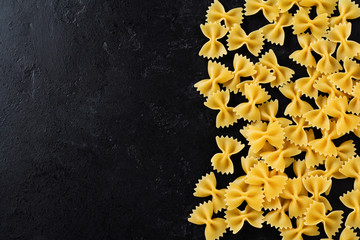 Farfalle raw pasta on black concrete background. Cooking concept. Top view with copy space.