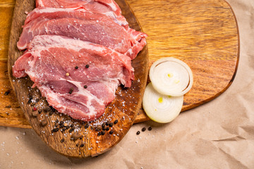 a raw pork wooden Board with pepper, onion, salt