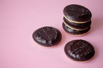 A pile of Jaffa cakes. Cookies covered with dark chocolate and filled with pink strawberry or cherry marmalade. Delicious biscuits isolated on pink background with copyspace