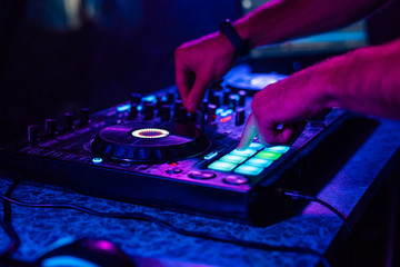 Obraz premium hands of a DJ playing music on a mixer at a concert
