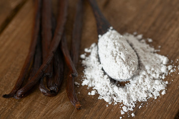 vanilla beans with aromatic sugar on dark wooden surface