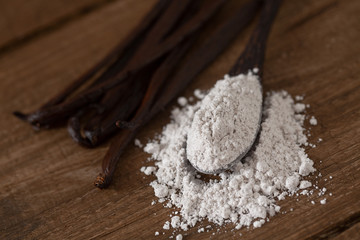 vanilla beans with aromatic sugar on dark wooden surface
