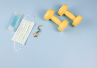 Hand Sanitizer , Disposable Hygienic Mask,medical pill or vitamin and dumbbell  on blue  background with copy space . protection against pm2.5 and COVID-19 concept.