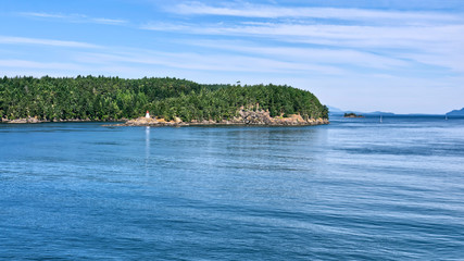 Naklejka premium beautiful Southern Gulf Islands in the Strait of Georgia from the ferry. Islands with evergreen conifers and turquoise sea water on a bright sunny day. Trip from Vancouver to Victoria, Canada
