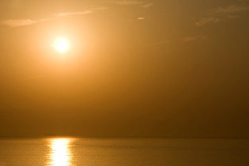 Fototapeta na wymiar The sun at dawn shines over the sea and the beach