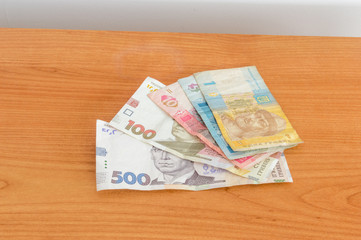 Ukrainian hryvnia banknotes on wooden table.