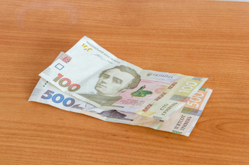 New Ukrainian hryvnia (UAH) banknotes on wooden table.