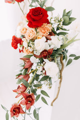 Decor of a stylish wedding ceremony. The decoration of the arch with red roses and wedding floristry. Modern trends in wedding bouquets.