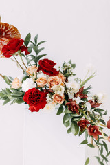 Decor of a stylish wedding ceremony. The decoration of the arch with red roses and wedding floristry. Modern trends in wedding bouquets.
