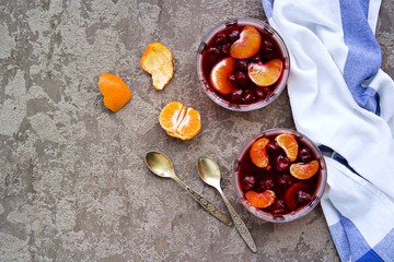 Dessert, sweet fruit jelly with cherries and tangerines in portioned bowls on a gray concrete background. Lenten desserts. Desserts without baking. Copyspace.