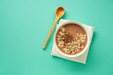 Chocolate smoothie bowl with oatmeal and flax seeds on a mint background