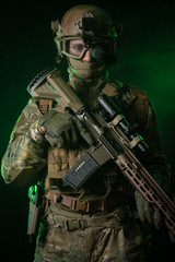 Fototapeta premium a soldier in military clothing with a night vision device and on a dark background