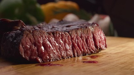 The cook cuts off a piece of steak with blood, roast with blood, meat fiber.