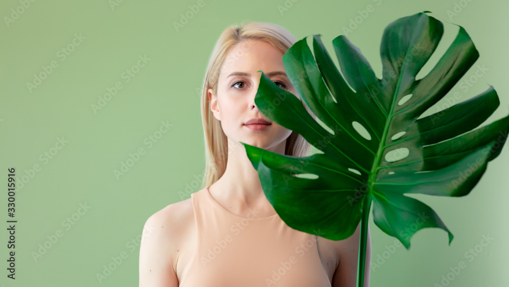 Poster blonde woman in flesh-colored clothing with palm leaves