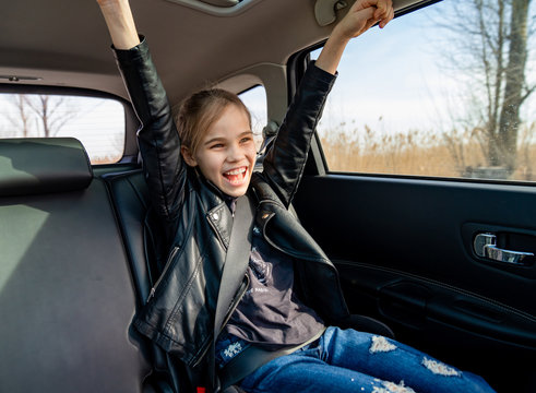 a teen girl in jacket rejoice in seat of car