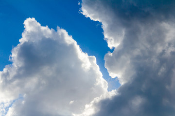 White and dark grey storm clouds on the blue sky