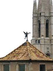 Girona, Spain. Weathervane "trumpeter" with The Collegiate Church of Sant Feliu on the backward plane,  isolated on white background